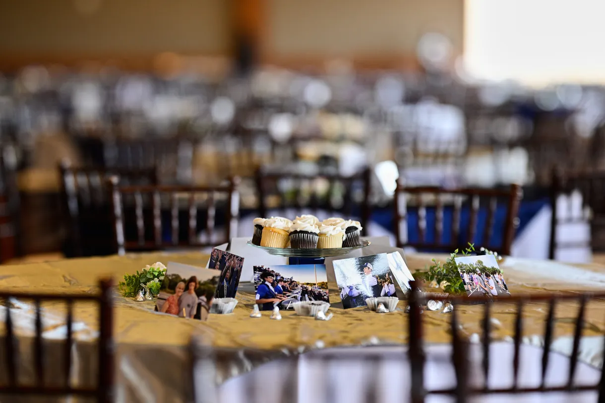A celebration table set with cupcakes and framed photographs before guests arrive