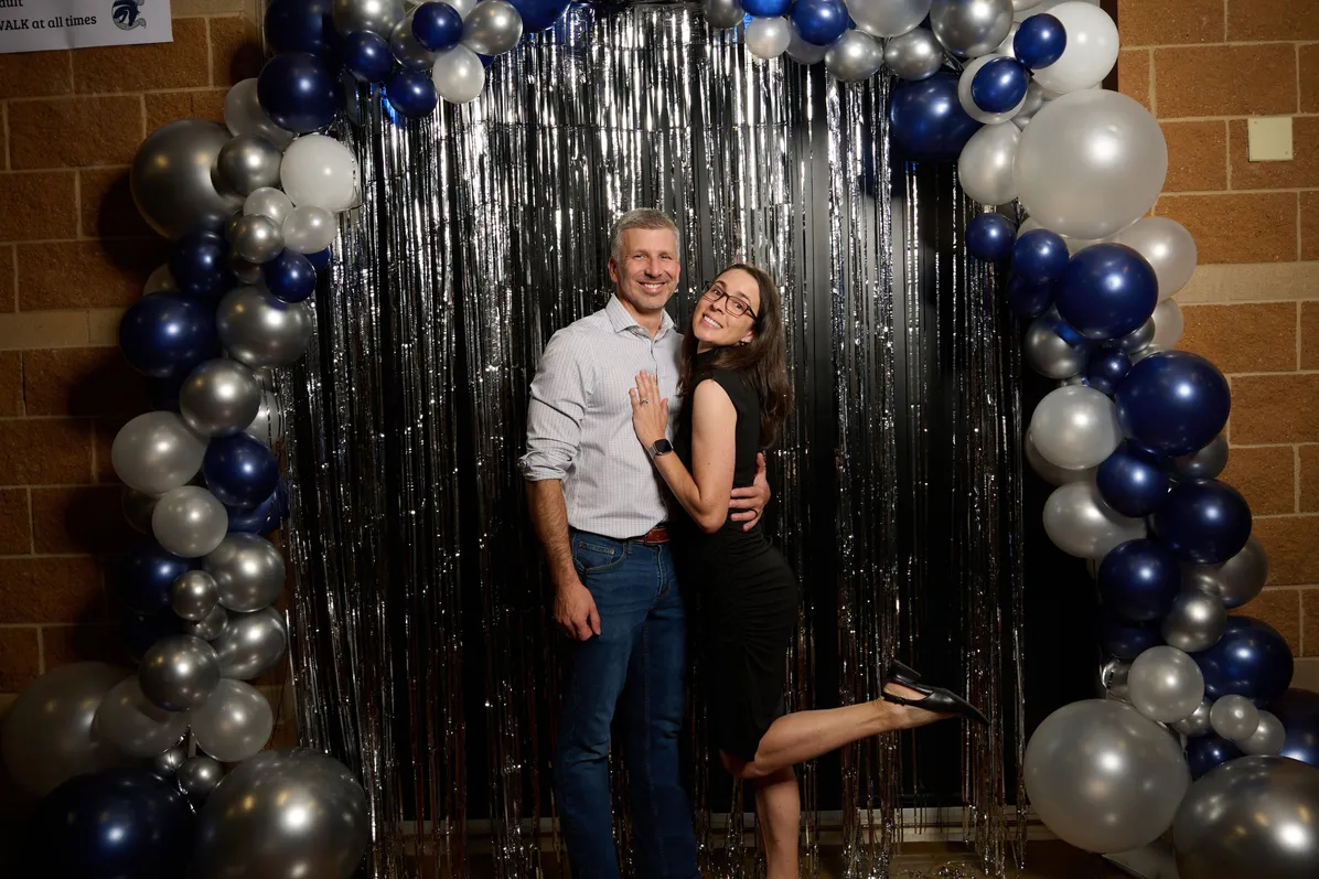 Couple posing at a balloon-decorated event backdrop