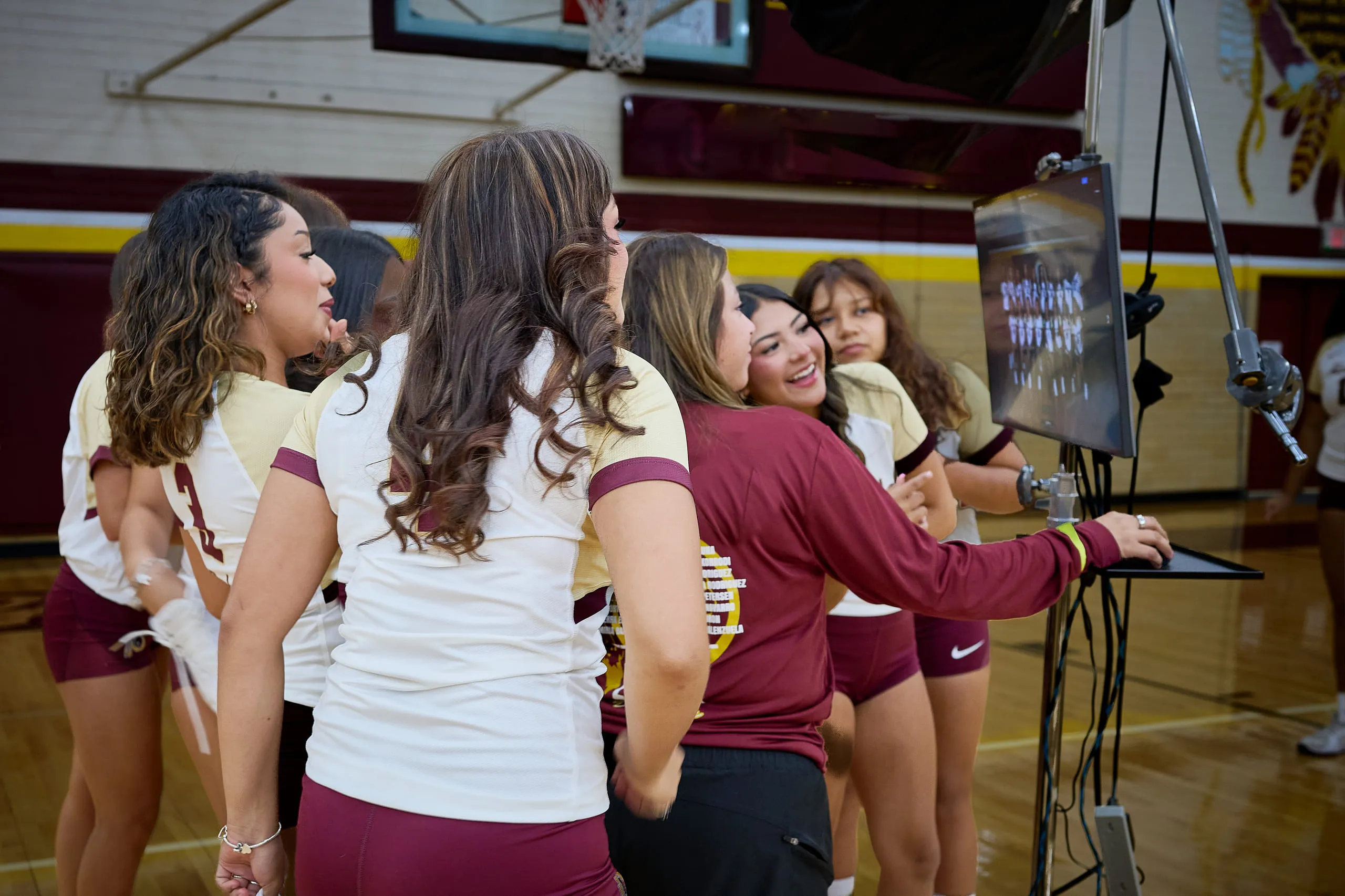 Volleyball athletes reviewing their media-day photos together beside the on-set display