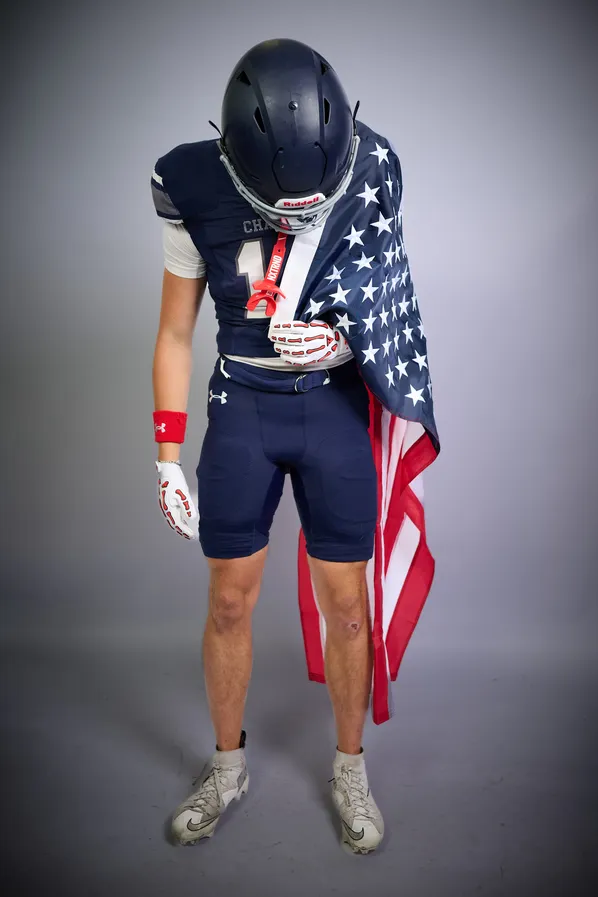 A football athlete draped in an American flag against a studio backdrop