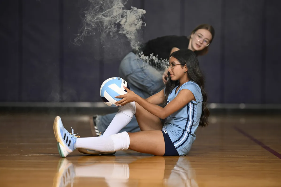 Volleyball athlete seated with a ball during a stylized media-day portrait