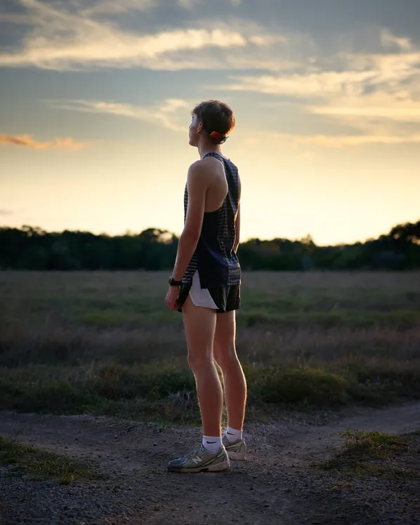 Track athlete at sunset, photographed from behind on an open field