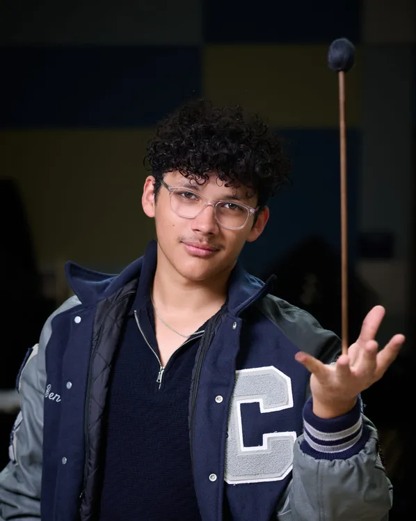 A senior in a letterman jacket tossing a percussion mallet