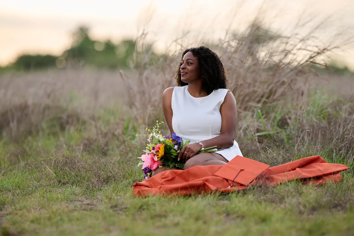 Seated portrait in tall grass with a bouquet at golden hour